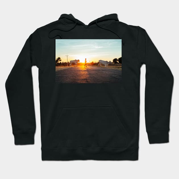 Silhouette of Boy Leading Cattle Across Road at Sunset in Burmese Countryside Hoodie by visualspectrum